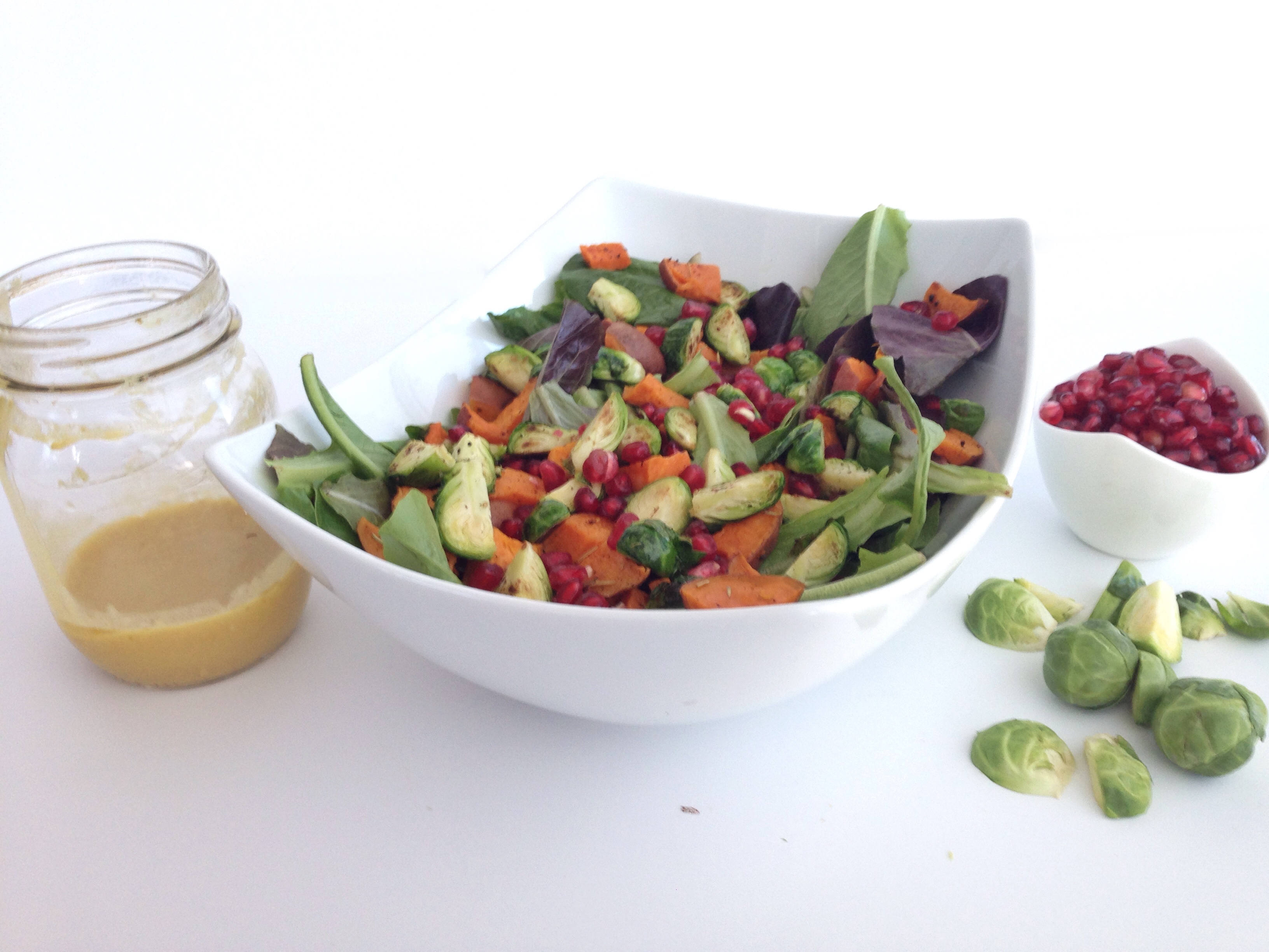 simple festive salad with dijon ginger dressing nourishing sweet potatoes brussels sprouts and pomegranate seeds